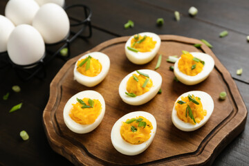 Board and holder with eggs, green onion on dark wooden background. Easter celebration