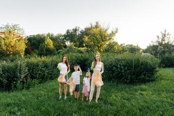A group of adults and children together at sunset is engaged in garbage collection in the park....