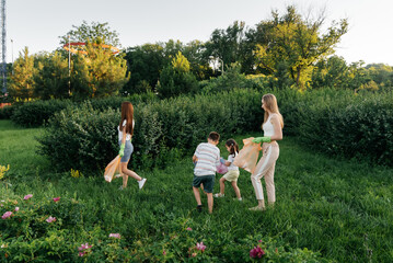 A group of adults and children together at sunset is engaged in garbage collection in the park....