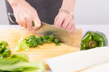 Cut vegetables on a wooden chopping board with both hands