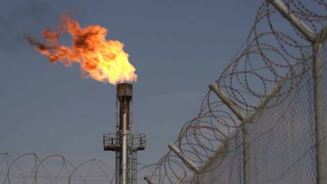 Flame from chimney. Barbed wire. Associated petroleum gas. Oil Field. Fire from pipe.