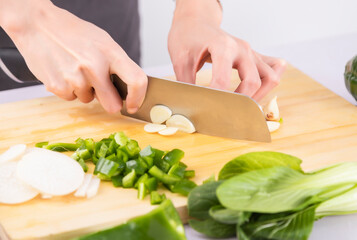 Cut vegetables on a wooden chopping board with both hands