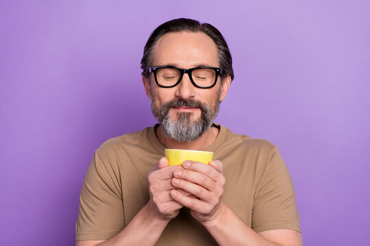 Portrait of handsome dreaming peaceful man feel nice smell of yummy coffee with closed eyes isolated on violet color background