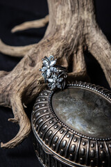 Silver ring on a wooden branch on a black background. Beautiful women's accessory