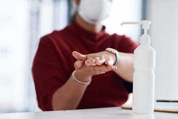 Fototapeta na wymiar Proper hand hygiene can reduce the spread of germs. Closeup shot of an unrecognisable businesswoman using hand sanitiser in an office.
