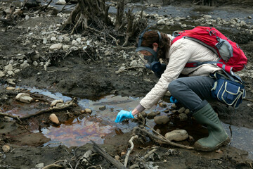 Environmentalist at Work in a Riverbed taking Soil and Water Samples