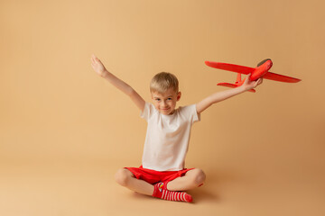 Adorable little boy playing with red airplane on the light background. Children and entertainment...