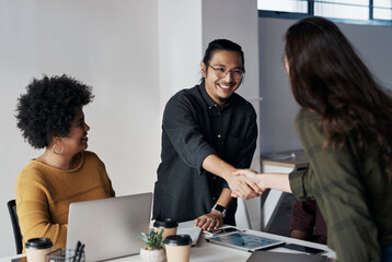 Its been a pleasure doing business with you. Cropped shot of a group of young businesspeople greeting each other with a handshake before sitting down in the office.