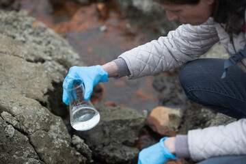Biologist Using Conical Flask Chemistry Glassware to Examine Sample of Water On Location