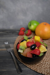 Fresh fruit salad, top view in a bowl on wooden background, vegetarian food concept