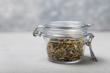 A jar of herbal tea on a light gray background. Detox and immunity drink. A mixture of herbs. Copy space.
