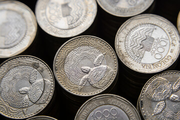 Pile of Colombian coins of 500 and 1000 denominations over wooden background. Ideal for economy, money, banks, save money and finance.
