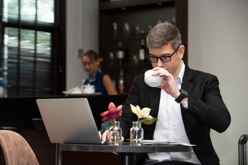 business man sitting at cafe working on laptop computer 