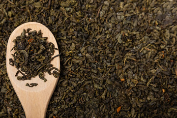 Green tea leaves. Dry green tea leaves in a wooden spoon.Background of dry green tea leaves.