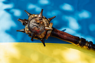 mace with emblem of Ukraine trident on blue and yellow national Flag of Ukraine. War concept....