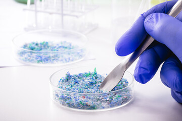 hand of traces of plastic and microplastic in petri dish, analyzed in laboratory, study of...