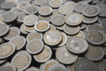 Pile of Colombian coins of 500 and 1000 denominations over wooden background. Ideal for economy, money, banks, save money and finance.
