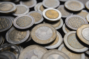 Pile of Colombian coins of 500 and 1000 denominations over wooden background. Ideal for economy, money, banks, save money and finance.
