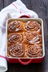 Traditional cinnamon buns with icing on a wooden table. Rustic style.