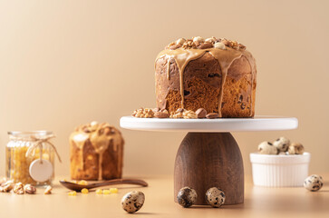 Caramel glazed Easter cakes decorated with nuts on pastel background. Easter composition with cakes, nuts, raisins and quail eggs. Easter background with copy space for your design.
