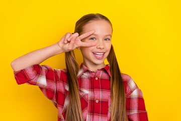 Photo of funky sweet schoolgirl wear checkered shirt showing v-sing cover eye isolated yellow color background