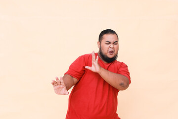 Fat asian guy refusing gesture, warning by giving palm while shouting isolated on cream background