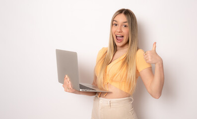 Fototapeta premium Image of cheerful amazed young woman with thumb up standing isolated over white background using laptop computer. Looking camera.