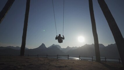 4K HDR A young man on a swing on a perfectly clear day enjoying the sunset in Riaño, Castilla y Leon, Spain