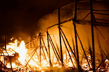 Burning collapsing wooden bridge in a raging flame close-up. Bridge on fire at dark night. Fiery...