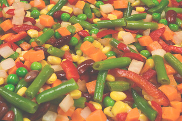 Sliced vegetables, corn, beans, peas, carrots, sweet peppers background.