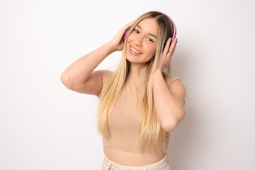 Smiling pretty young woman wearing headphones listening music isolated over white background