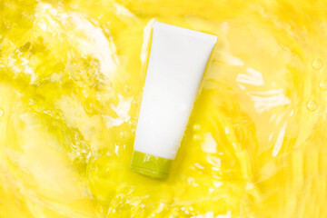 Tubo de crema facial y de cuerpo flotando sobre agua con olas sobre un fondo amarillo. Vista...