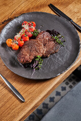 two steaks on a dark plate with sauce and cherry tomatoes on a dark background. banner for advertising meat and steak restaurant