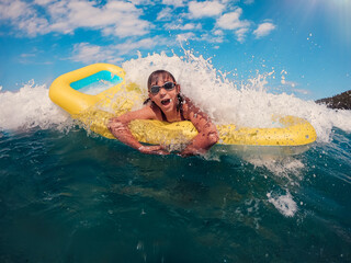 Girl on the airbed getting splashed by the wave