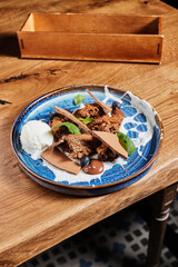 
chocolate savory dessert with ice cream on a vintage blue plate on a table in a restaurant, pastry shop banner