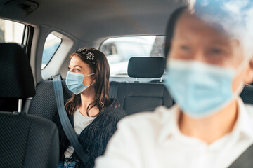 Fototapeta na wymiar A woman wearing a protective mask on the back seat of a taxi car