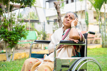 Deep thinking disabled senior woman on wheelchair at park - concept of depression, loneliness and...