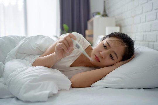 Asian woman feeling sick. She was in bed and her body temperature was measured.