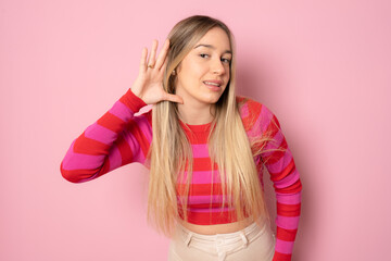 Young caucasian woman wearing casual sweater smiling with hand over ear listening an hearing to rumor or gossip. Deafness concept.