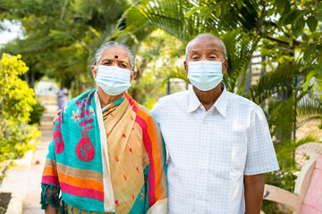 Senior couples with medical face mask during morning walk at park - concept of covid-19 coronavirus...