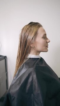 A girl with long blond hair is getting her hair done in a chair at a hairdresser