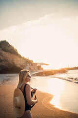 young woman in a swimsuit with a beautiful figure on the seashore at sunset. Selective focus