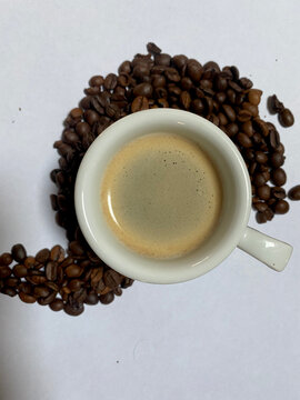Closeup of espresso with foam and coffee beans around on white background © Cenusa Silviu Carol