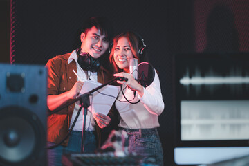 Asian couple singers in a recording studio using a studio microphone with passion in music recording studio