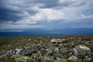 green mountains covered with forest, storm clouds, view from the top with stones