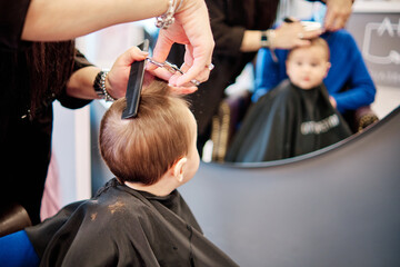 Toddler child getting his first haircut in a beauty salon
