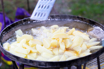 Potatoes are fried in a large frying pan in oil