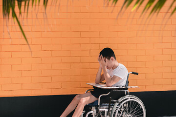 Fototapeta na wymiar Young man with disability have some things to think about that can lead to depression,Teenager boy sitting with tray for activities on wheelchair,Sad emotional or depression and mental health concept.