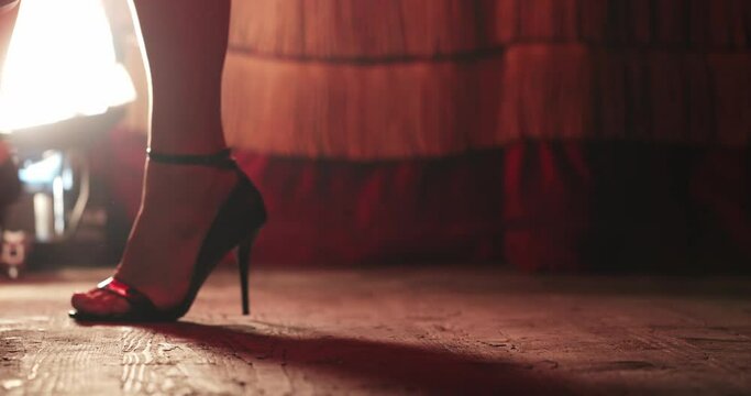 close-up of female legs in heels that scroll and knock with their heels on the floor. silhouette of the legs of a dancer that dances flamenco. close-up