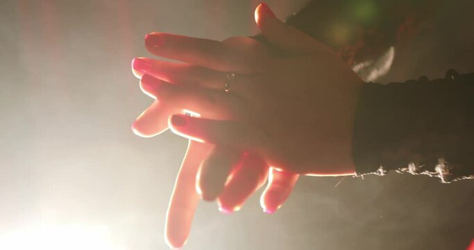 handclaps of a woman in a red dress, part of a flamenco dance in Spain. the girl's hands that clap in the backlight in the dark. close-up